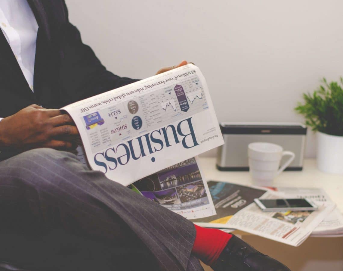 man-reading-newspaper-while-sitting-near-table-with-935979