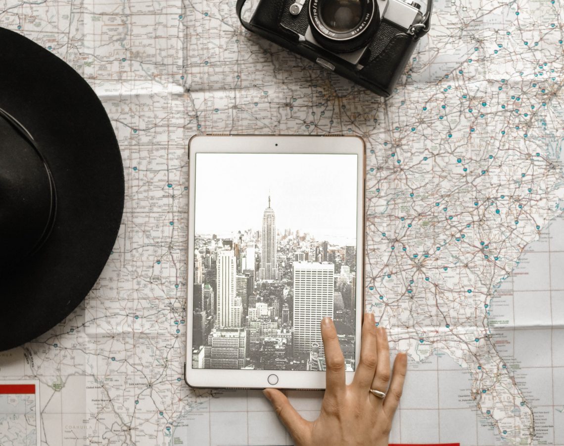 flat-lay-photography-of-person-touching-silver-ipad-on-world-1051077
