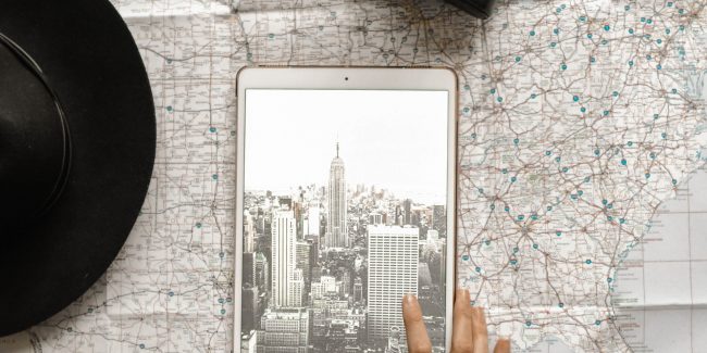 flat-lay-photography-of-person-touching-silver-ipad-on-world-1051077