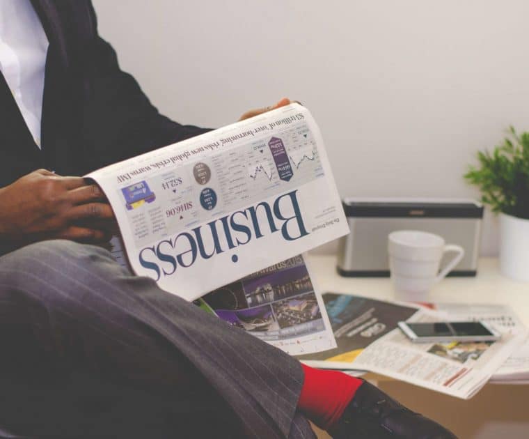 man-reading-newspaper-while-sitting-near-table-with-935979