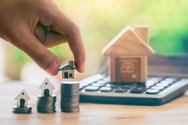 House On Coins And House Put On Calculator. Man's Hand Putting H